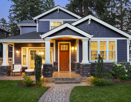 Beautiful new home shown with lights on at dusk.